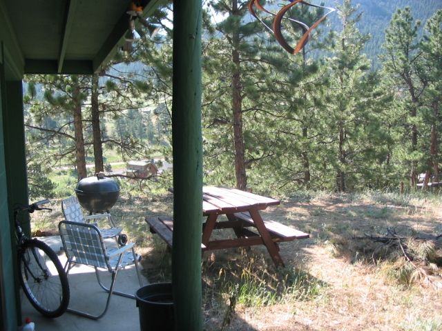 View from the covered patio of a picnic table among ponderosa pines on a sunny hillside